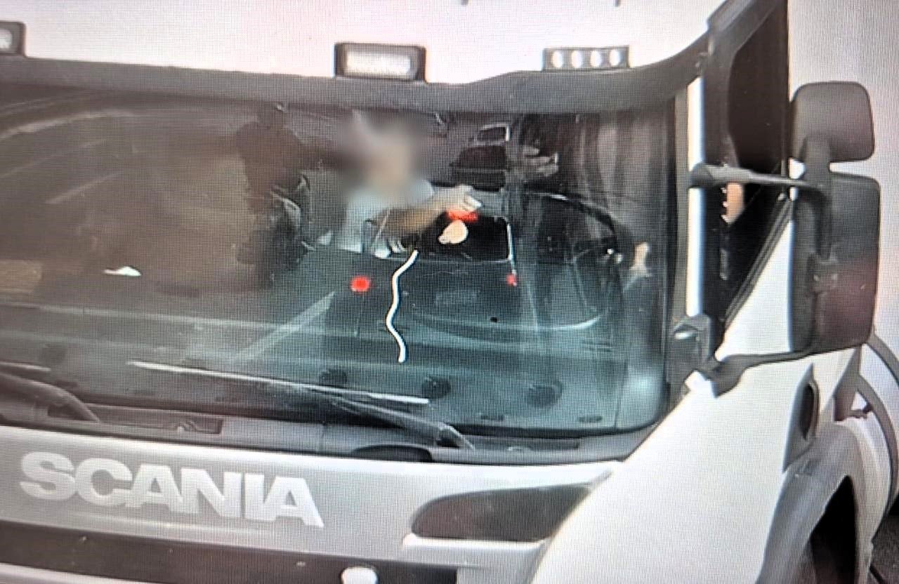 Foto flagra criança segurando volante de caminhão enquanto motorista usa celular em SC